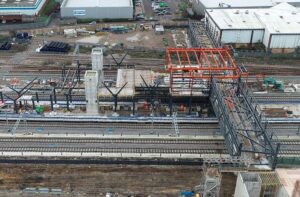 the grey steelwork of the station's overbridge and red orange outline of the concourse over the train tracks