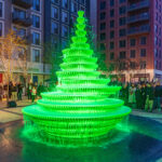 a bright green fountain with people watching around it